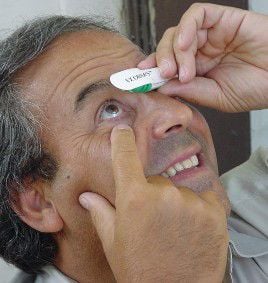 A Man Places a Small Piece of Paper Over His Eye